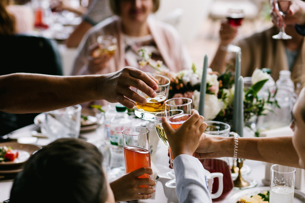 Intimate wedding guests at their table saying cheers with alcoholic beverages