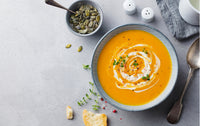 Pre-made soup displayed in a bowl with a small bowl of pine nuts next to it