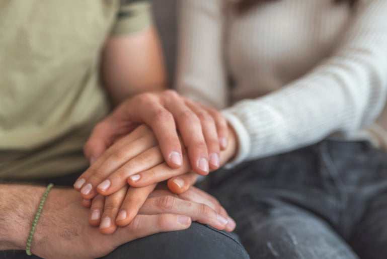 Two people holding their hands on their knees comforting each other 