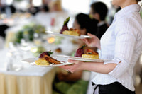 Waitress staff member serving dinner plates for Ely's Fine Foods Wedding catering services