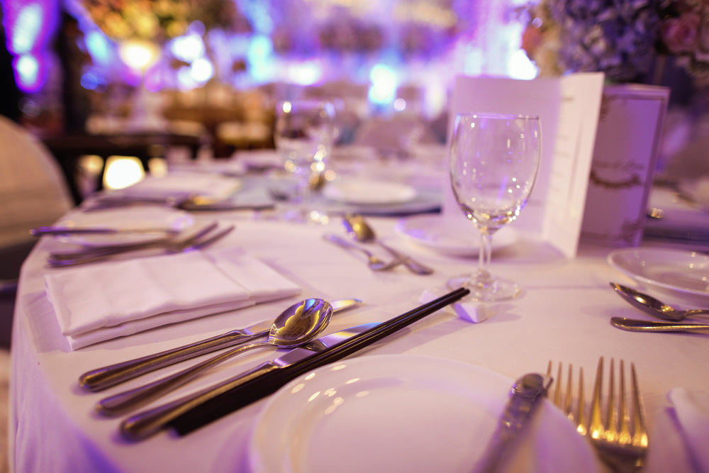 Set table with dish ware, white tablecloth, white plates, and white napkins